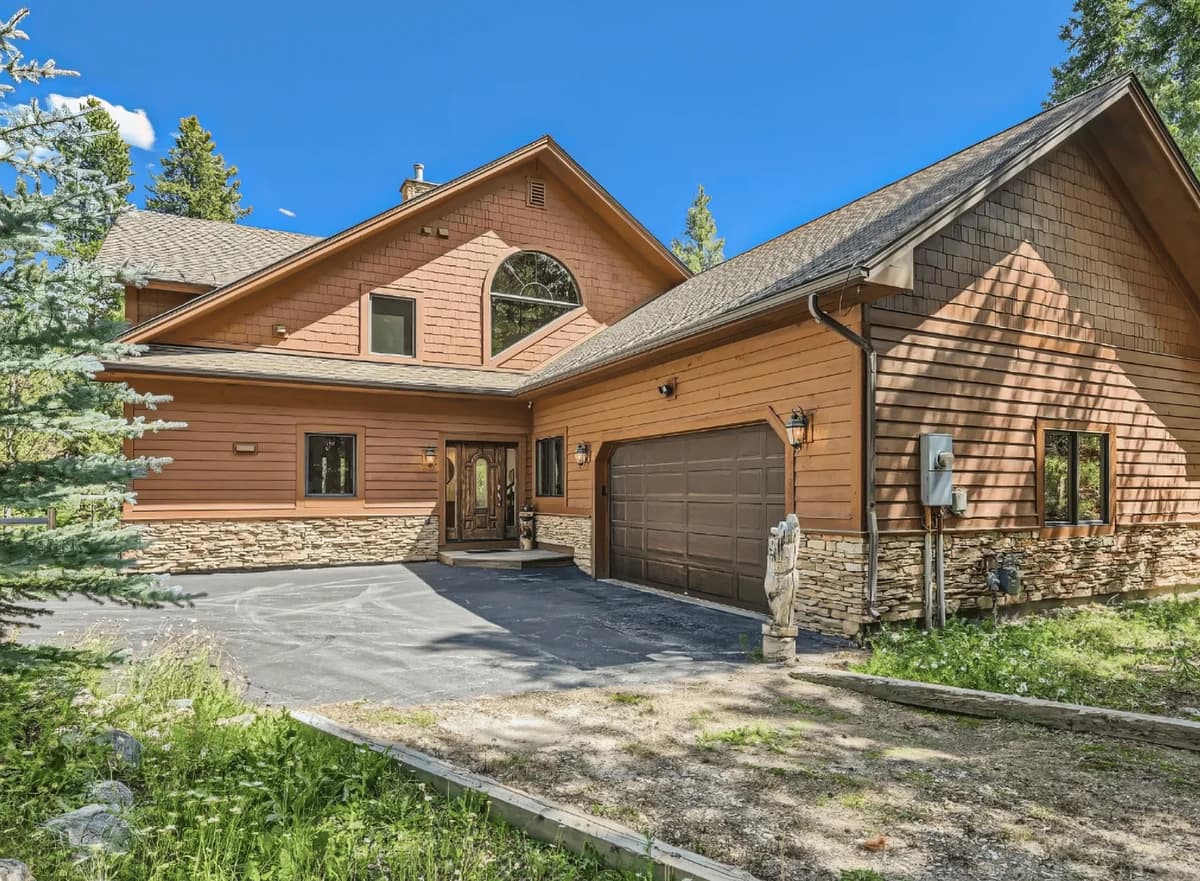 Modern brown timber and stone exterior with garage and driveway on sunny day