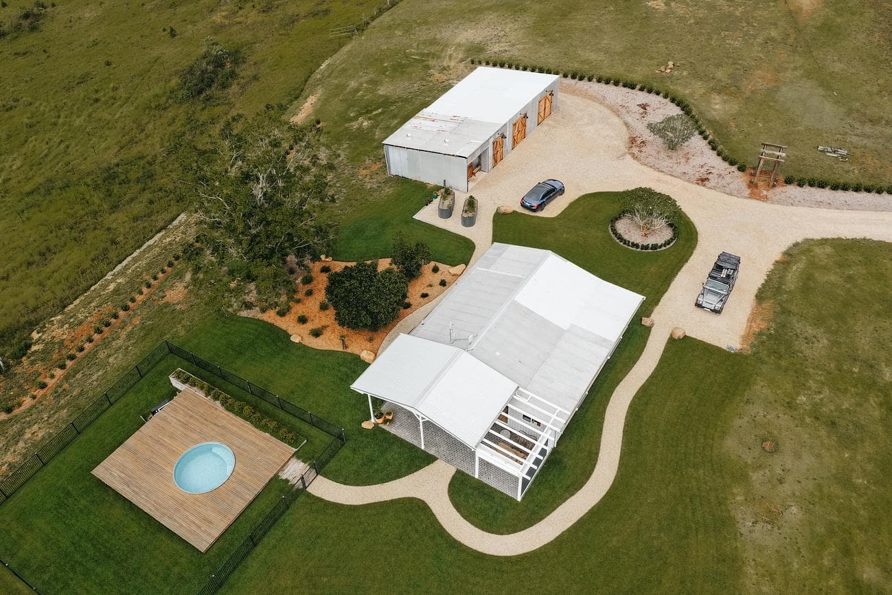 Aerial view of rural wellness facility with pool, white buildings, and green grounds