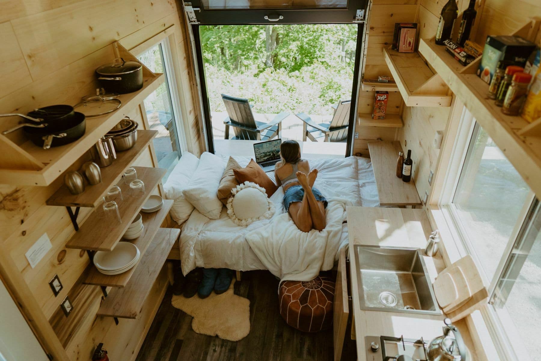 Overhead view of a tiny home cabin interior with bed, kitchenette, and outdoor patio access