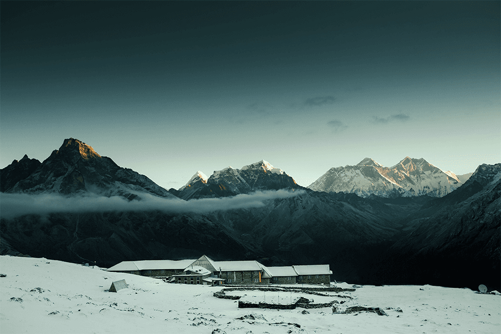 Mountain lodge nestled in snowy valley beneath snow-capped peaks