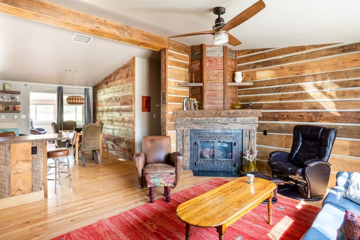 Rustic cabin interior with exposed wood beams, fireplace, and leather seating
