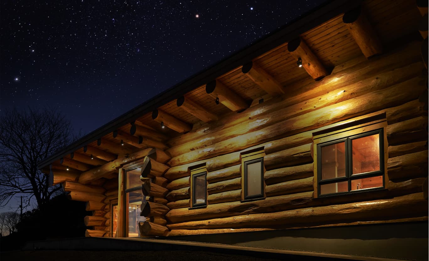Illuminated log cabin exterior at night under starry sky