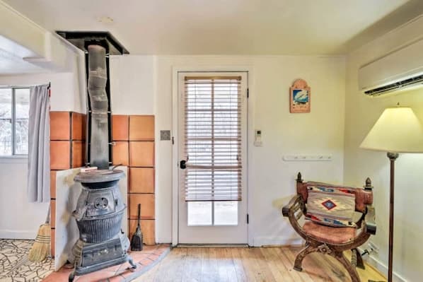 Bright cabin interior with wood stove, door to patio, and rustic furnishings