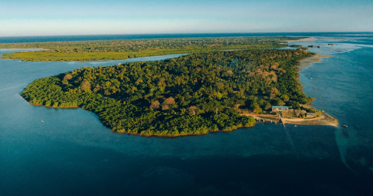 Aerial view of island lodge surrounded by turquoise water and lush forest