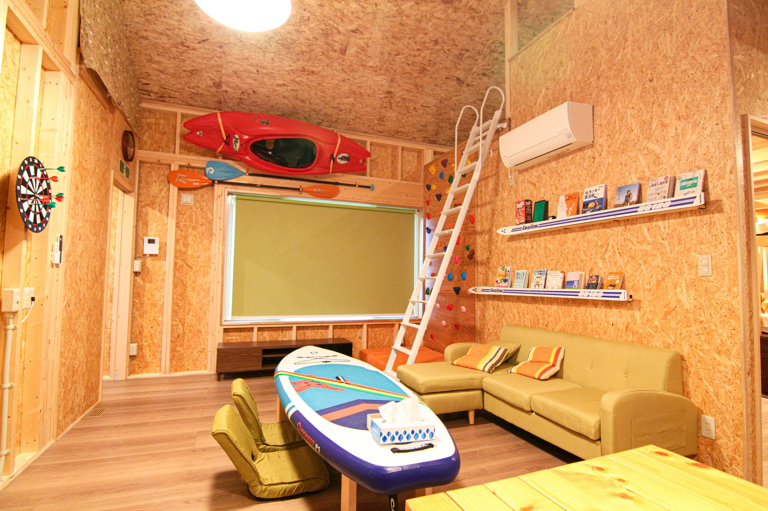Activity room with cork walls, yellow furniture, kayaks, and climbing wall