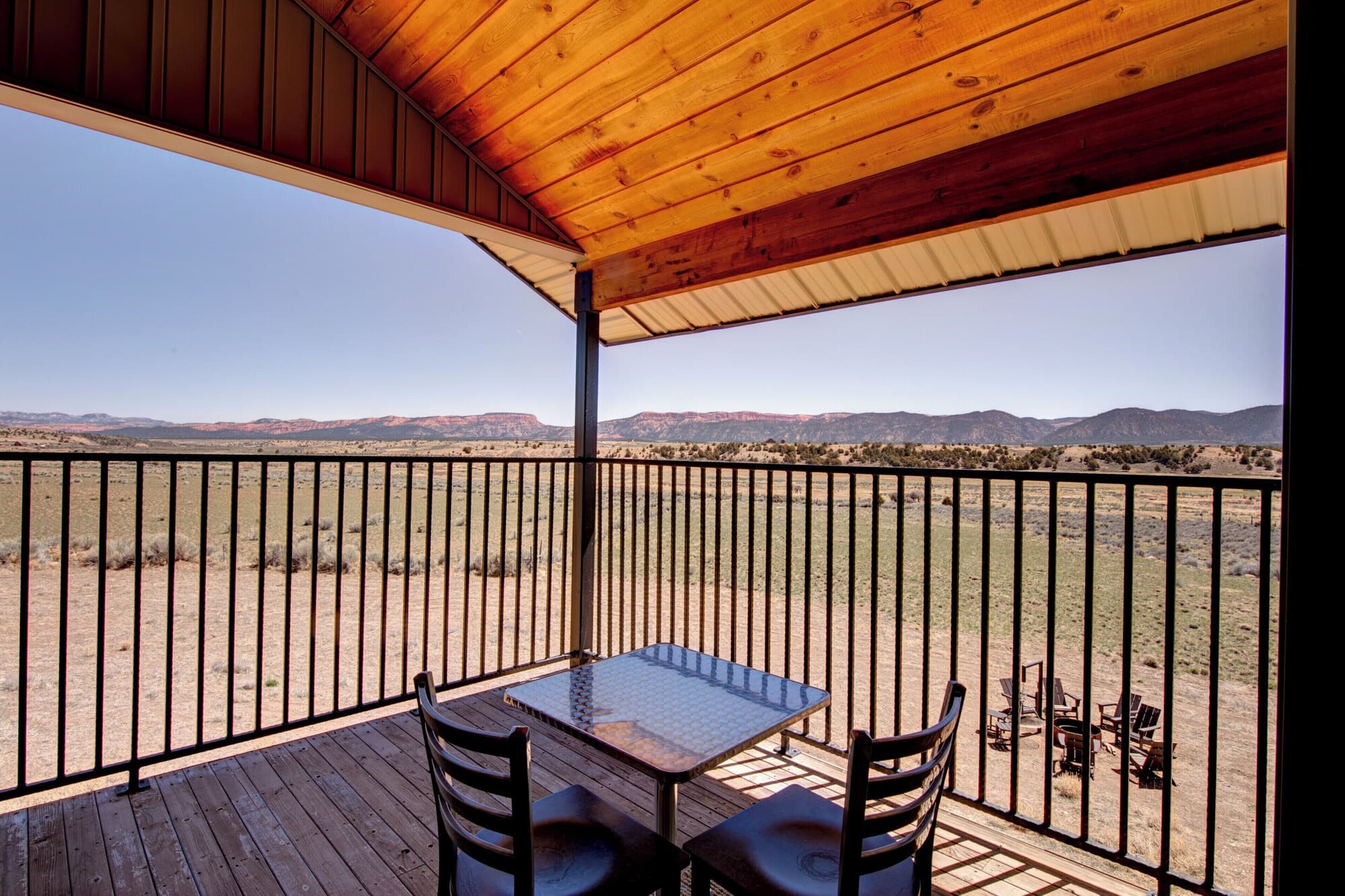 Wooden deck with table and chairs overlooking desert landscape and mountains