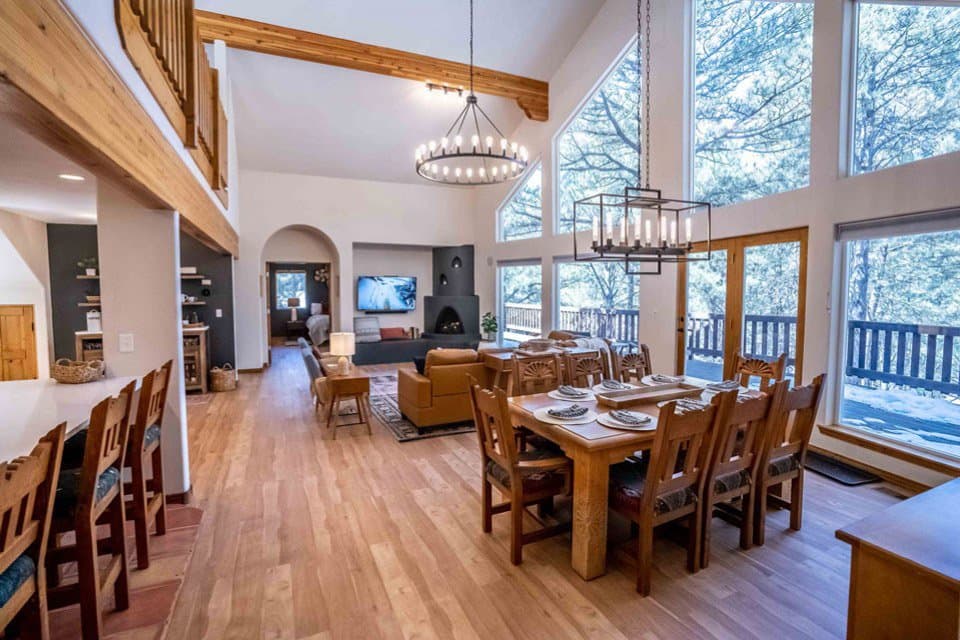 Open-plan dining and living room with exposed beams, large windows, and modern furnishings