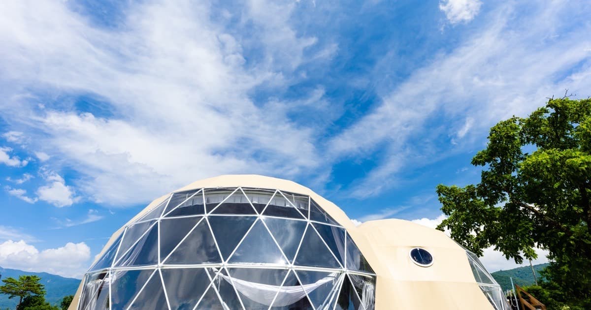 Geodesic dome structure with white frame and triangular panels under blue sky