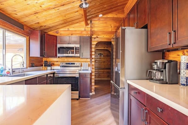 Modern kitchen with wooden ceiling, island countertop, and stainless steel appliances