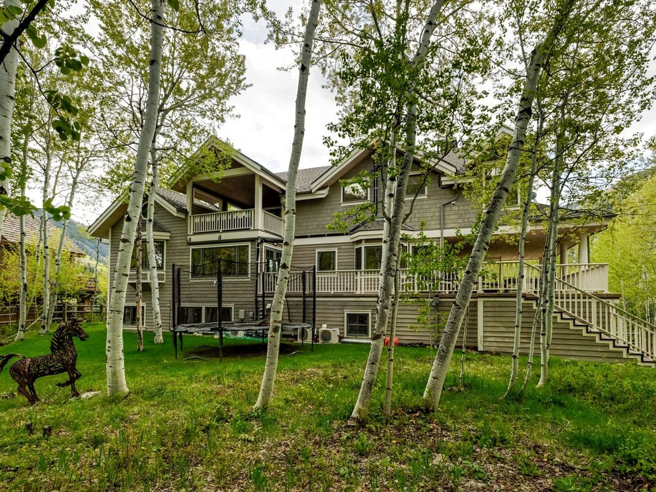 Modern multi-level cabin with decks nestled among birch trees on green lawn