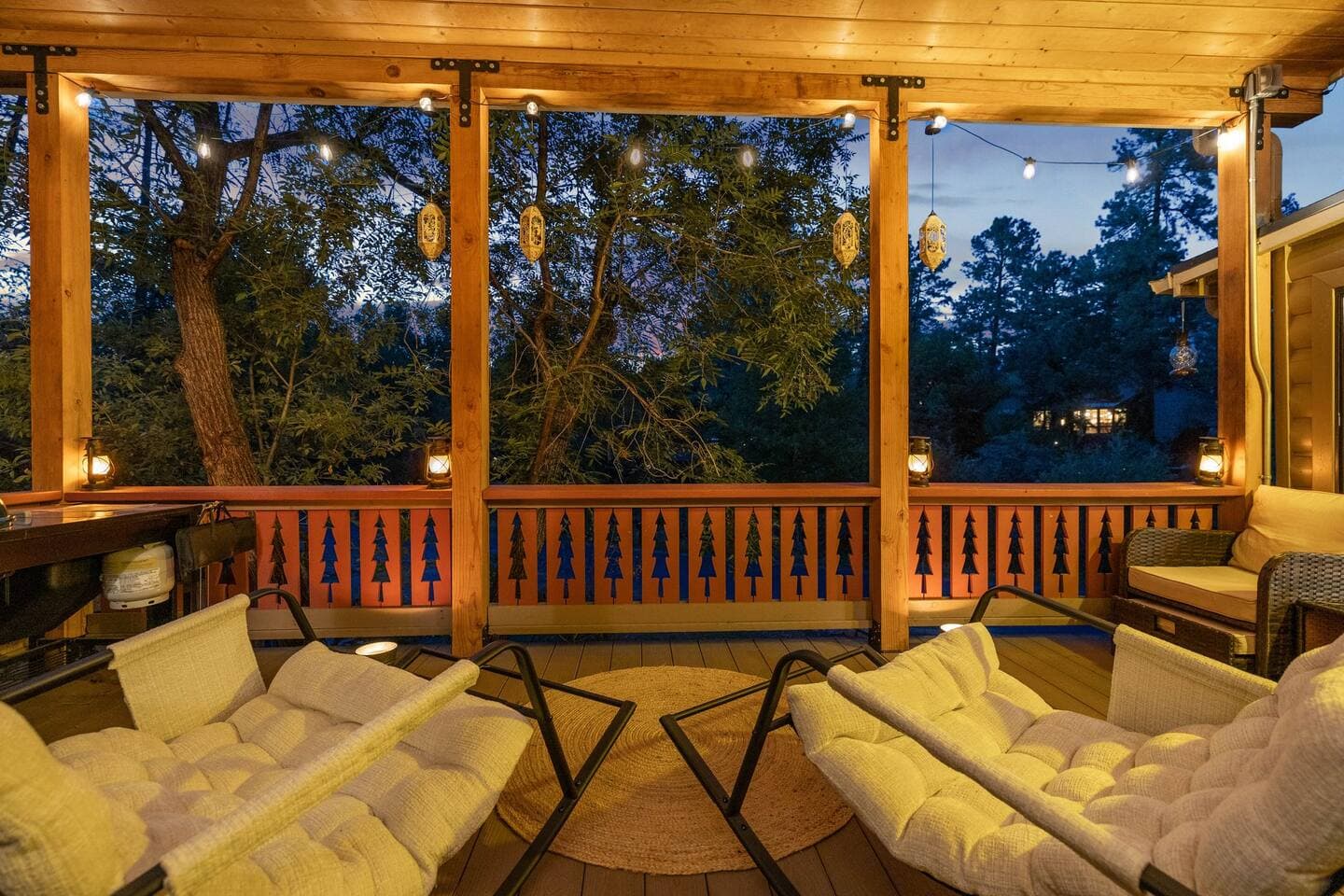 Illuminated wooden pavilion with comfortable seating overlooking forested landscape at dusk