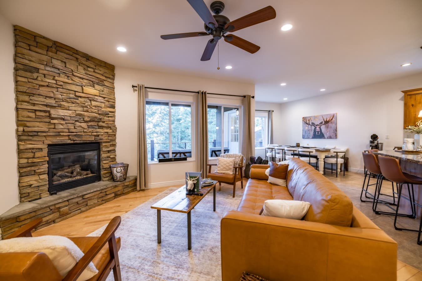 Bright modern living room with stone fireplace, leather seating, and mountain views through glass doors