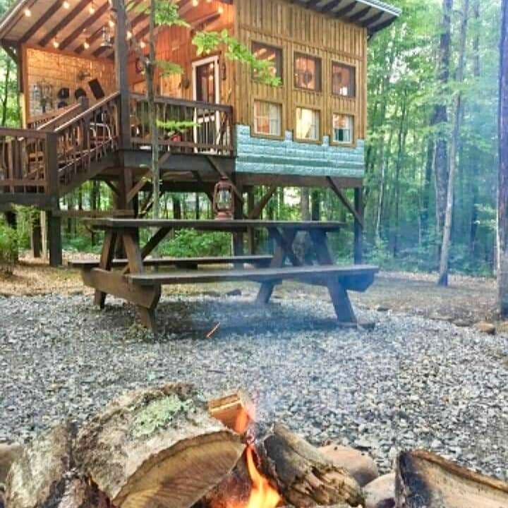 Wooden elevated cabin with picnic table and fire pit in forest setting