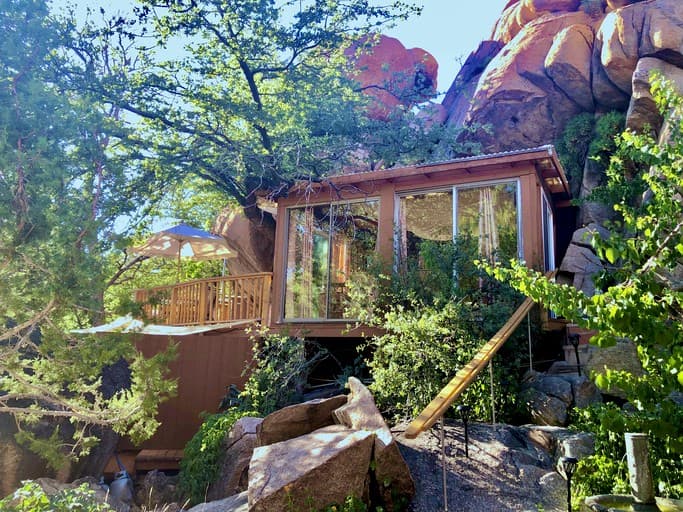 Modern cabin nestled among granite boulders with large windows and blue umbrella