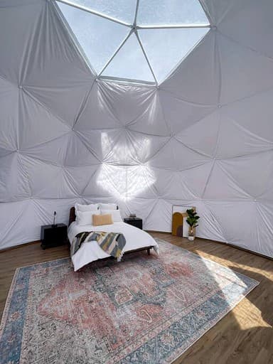 Geodesic dome bedroom interior showing bed and natural light through fabric panels
