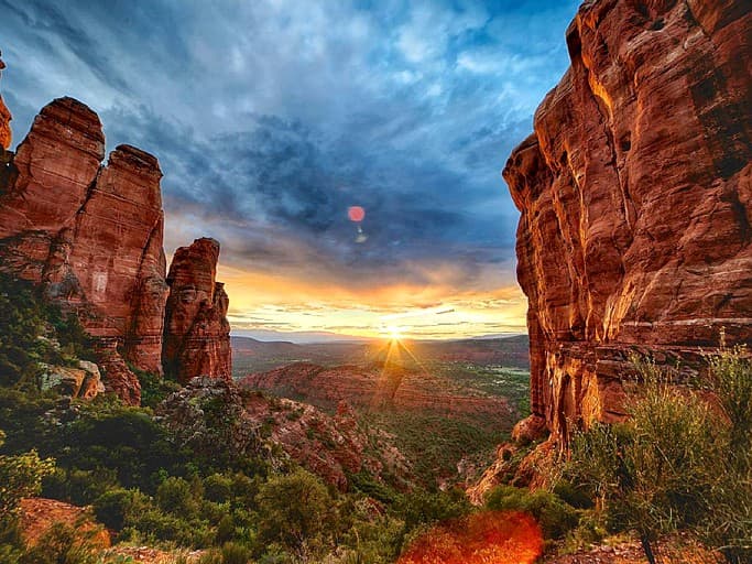 Sunset framed by red rock formations with golden light and blue sky