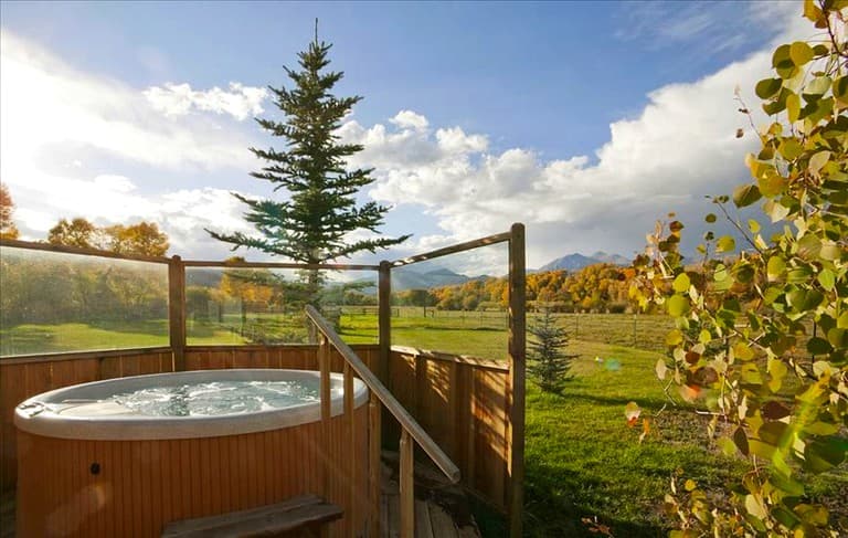 Hot tub on wooden deck overlooking mountain valley and autumn forest