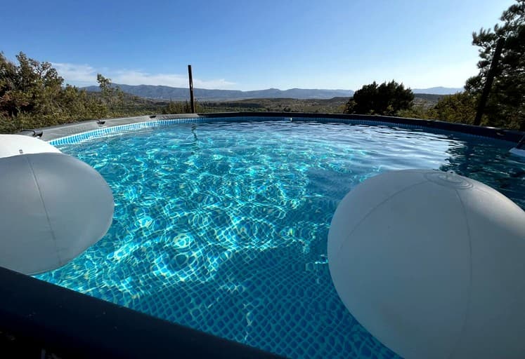 Crystal clear swimming pool with mountain valley views and desert landscape in background